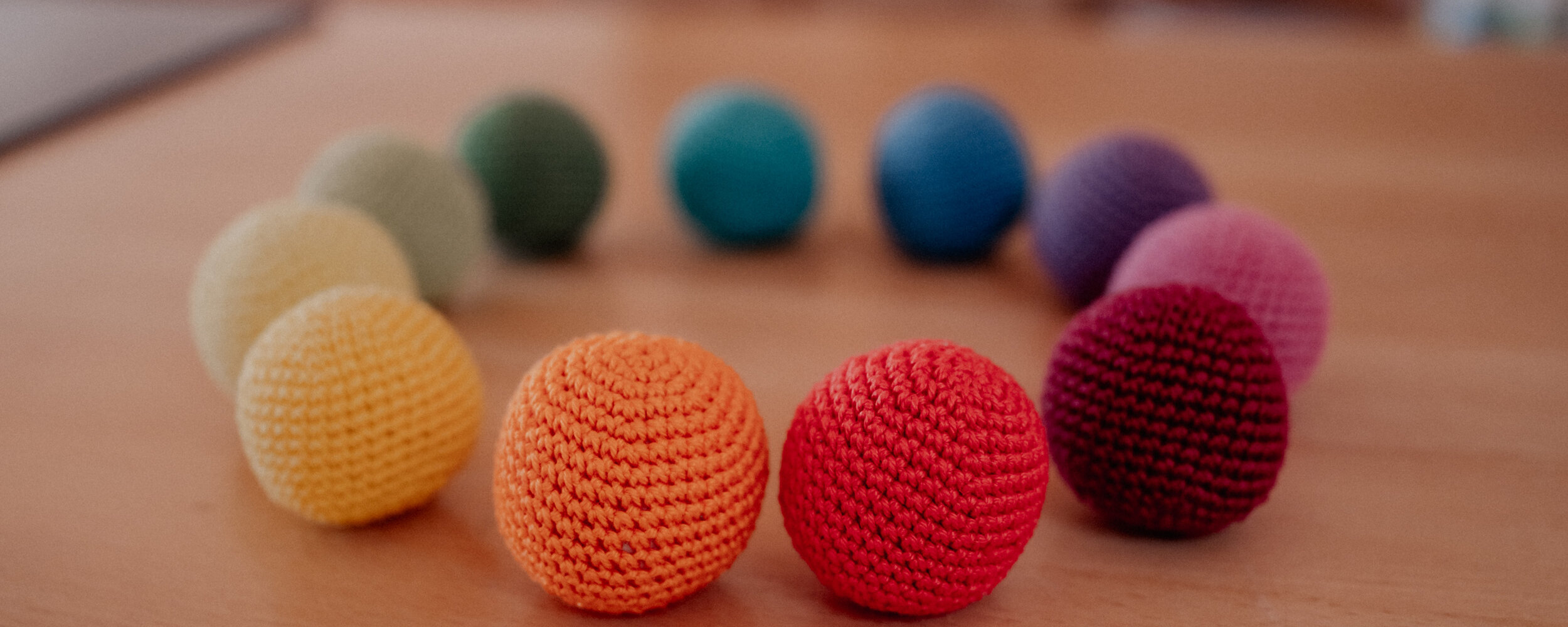 Bunte Stoffbälle auf einem Tisch, im Kreis angeordnet.